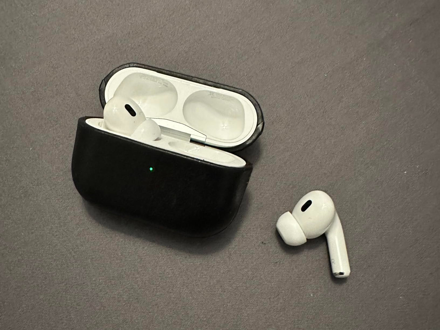Wireless earbuds with black charging case on a gray surface