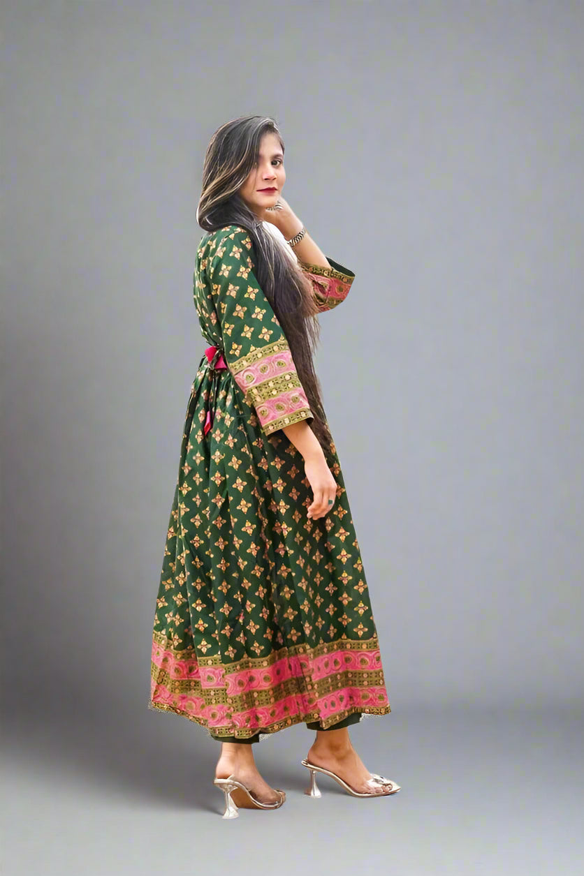 Woman wearing a green patterned dress with pink accents outdoors.