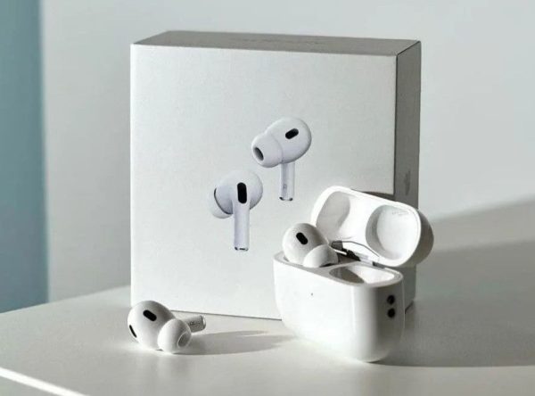White wireless earbuds with charging case on a light gray surface