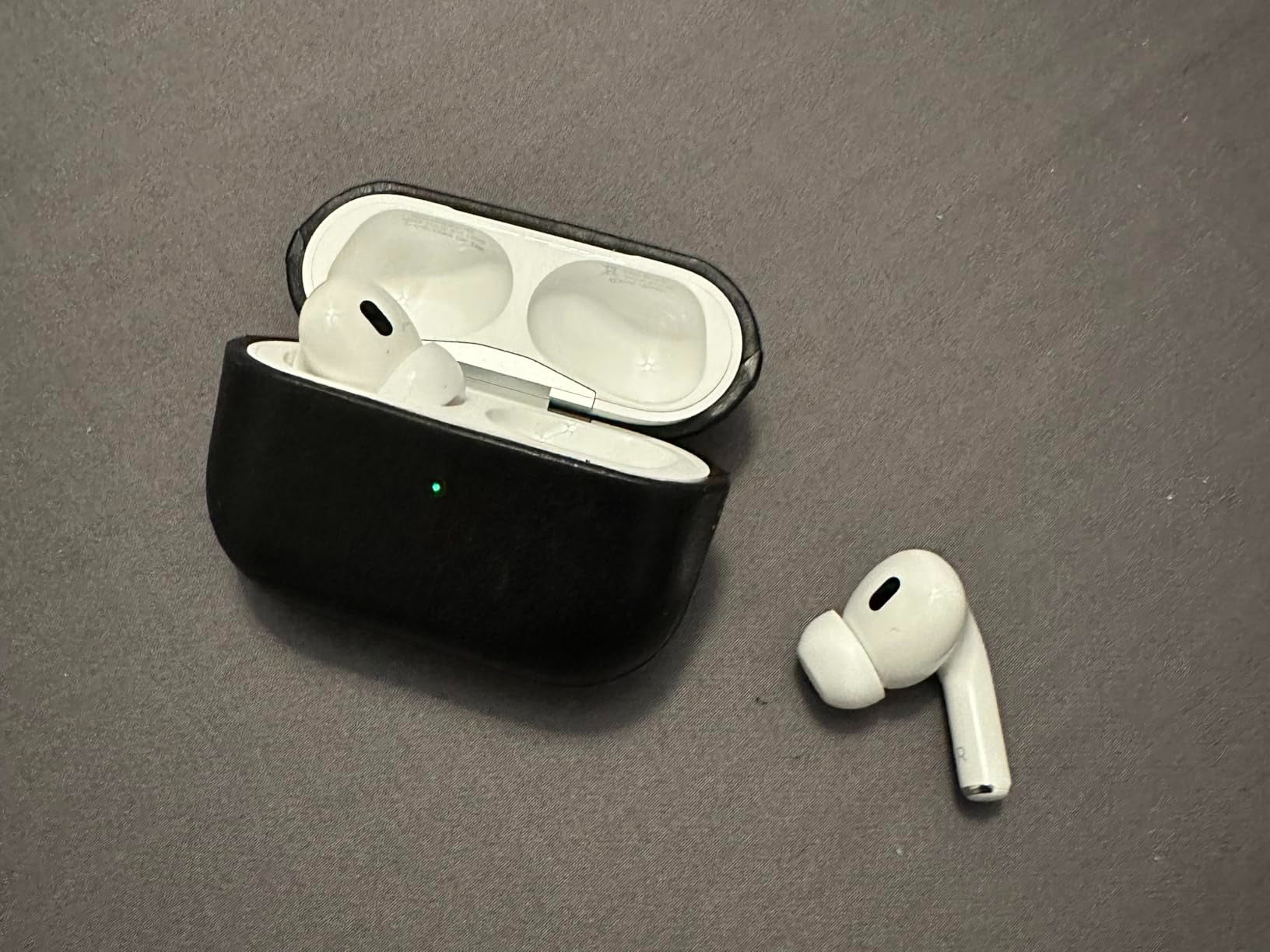 Wireless earbuds with black charging case on a gray surface