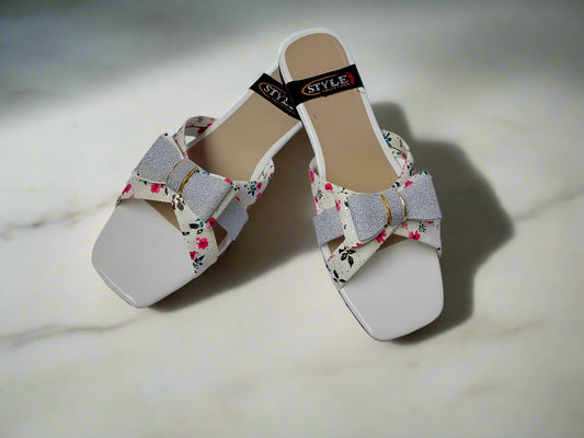 Pair of floral sandals with a bow on a marble surface