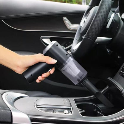 Hand using a black car vacuum cleaner inside a vehicle.